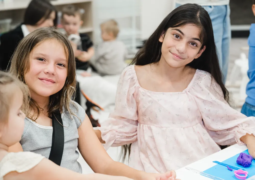 Two school-age children smiling together during a classroom activity