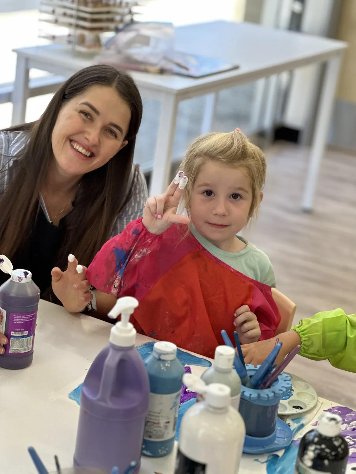 An educator and child smiling together during an art activity