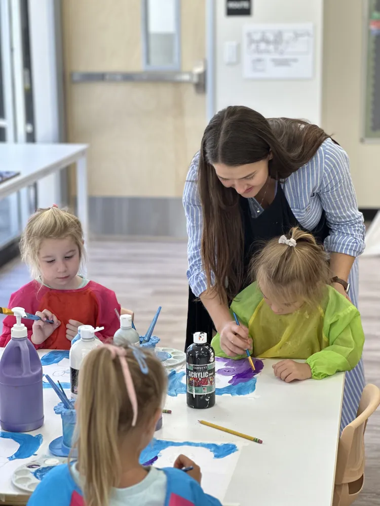 An educator guiding children through a colorful hands-on sensory activity